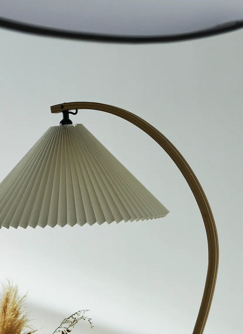 Close-up view of the Cozy Glow Lamp showcasing its beautifully crafted arched wooden frame and textured pleated lampshade, emphasizing the elegant design and soft lighting it offers.