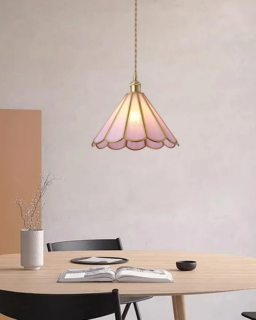 Butterfly pendant lamp with a pink stained glass scalloped shade and gold accents, hanging above a round wooden dining table set with an open book, ceramic bowls, and minimalist decor, creating a warm and inviting atmosphere.