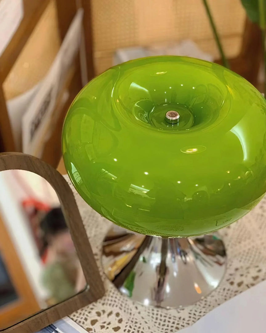 Close-up of the candle table lamp with a vibrant green glass dome-shaped shade and polished chrome base, placed on a lace-covered surface near a heart-shaped mirror, adding a cozy and decorative touch to the space.