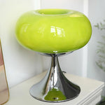 Load image into Gallery viewer, Candle table lamp featuring a bright green glass dome-shaped shade and a sleek polished chrome base, displayed on a white surface with a mirror edge and soft greenery in the background for a fresh, modern aesthetic.
