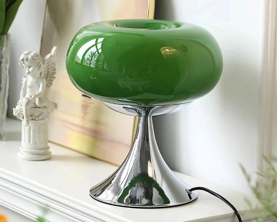 Candle table lamp with a glossy green glass dome-shaped shade and polished chrome base, styled on a white mantel alongside a decorative angel figurine and framed artwork, adding a modern and serene touch to the decor.