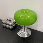 Load image into Gallery viewer, Candle table lamp with a vibrant green glass dome-shaped shade and polished chrome base, styled on a black wooden surface alongside a metallic abstract sculpture, creating a sleek and contemporary decor accent.
