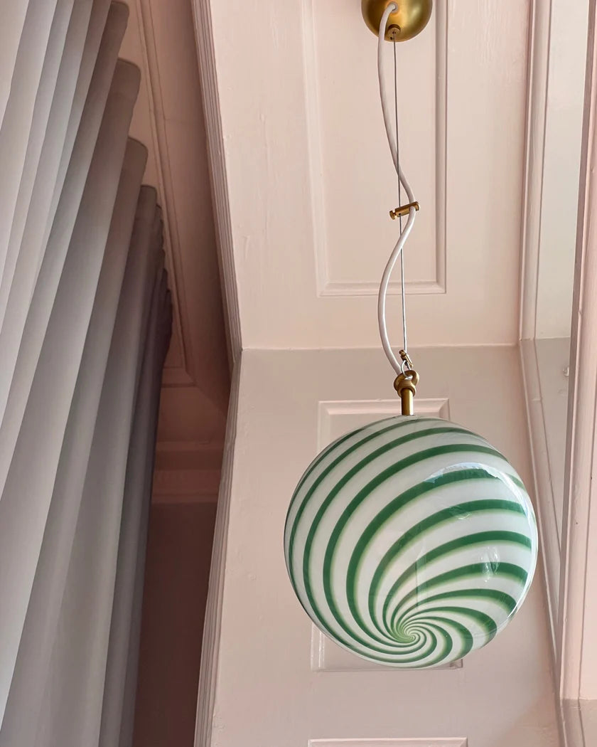 Green and white striped candy pendant lamp hanging in a stylish room with soft curtains and light-colored walls, casting a playful and vibrant glow to enhance the modern interior design.