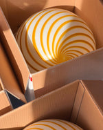 Load image into Gallery viewer, Candy pendant lamps with vibrant yellow and white spiral stripes, carefully packed in cardboard boxes, showcasing their bold design ready for setup or shipping.
