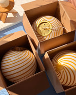 Load image into Gallery viewer, Candy pendant lamps with yellow and white spiral stripes, carefully packed in cardboard boxes, awaiting setup or delivery, showcasing their playful and vibrant design.
