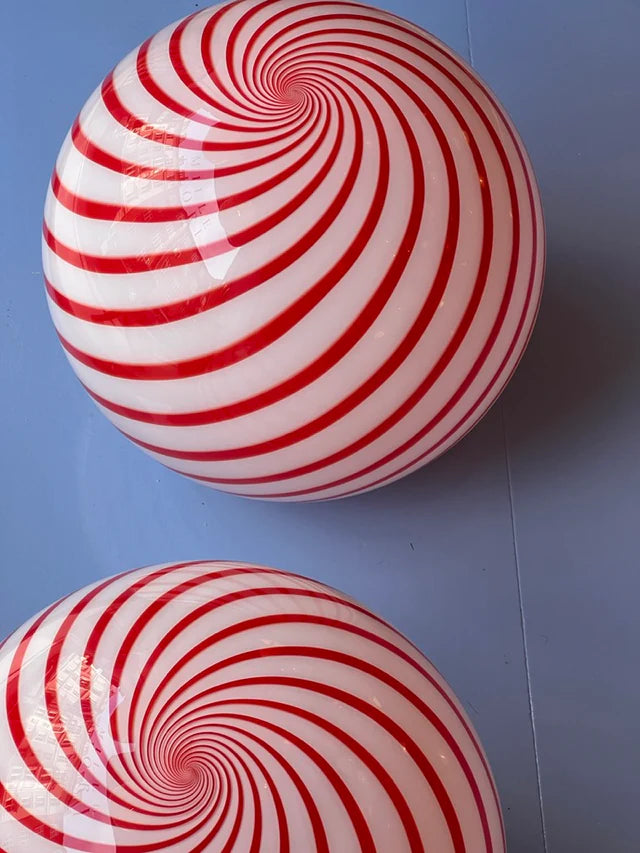 This Candy pendant lamp, featuring a bold red and white striped swirl pattern, adds a playful yet sophisticated charm to the space, creating an eye-catching focal point overhead.