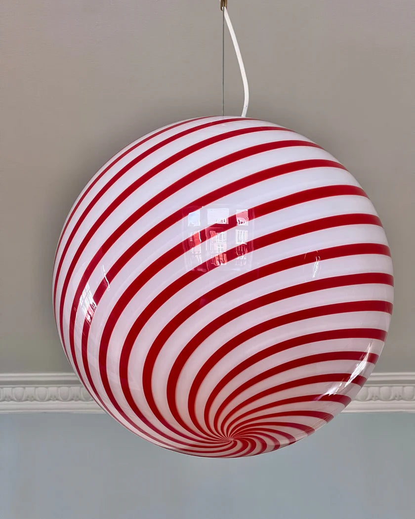 This vibrant Candy pendant lamp with red and white stripes hanging from the ceiling creates a visually striking atmosphere in the space, complementing the surrounding decor with its playful design.