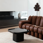 Load image into Gallery viewer, The Cépage Floor Lamp with a cluster of burgundy globe-shaped lights on a black stand, placed in a sleek living room featuring a plush brown leather sofa, a black modern coffee table, and a minimal fireplace with a ceramic vase accent on a console.
