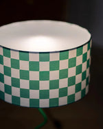 Load image into Gallery viewer, A close-up of a green and white checkerboard-patterned lampshade, capturing the fabric&#39;s fine texture and the soft glow emanating from within. The rounded edge and inner white lining create a balanced contrast, emphasizing the modern and playful design of this statement decor piece.
