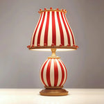 Load image into Gallery viewer, A whimsical Circus Table Lamp with a bold red and white striped design featuring a rounded base and matching lampshade, accented with playful pom-poms, placed against a neutral background to highlight its vintage-inspired charm and unique aesthetic.
