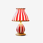 Load image into Gallery viewer, A studio shot of the Circus Table Lamp featuring a red and white striped shade with pom-pom accents and a matching round base, set against a clean white background to highlight its playful and vintage-inspired design.
