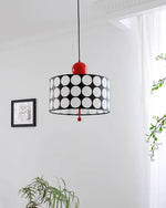 Load image into Gallery viewer, Artistically placed Metal Lattice Pendant Lamp with a black and white circular design and vibrant red accents, casting soft light in a modern art gallery setting, enhancing the ambiance near framed artwork and greenery.
