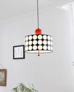 Load image into Gallery viewer, Artistically placed Metal Lattice Pendant Lamp with a black and white circular design and vibrant red accents, casting soft light in a modern art gallery setting, enhancing the ambiance near framed artwork and greenery.
