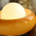 Load image into Gallery viewer, Close-up detail of the Crostata Table Lamp, highlighting the smooth orange glass bowl and the softly glowing white orb, showcasing the lamp&#39;s refined texture and warm illumination.
