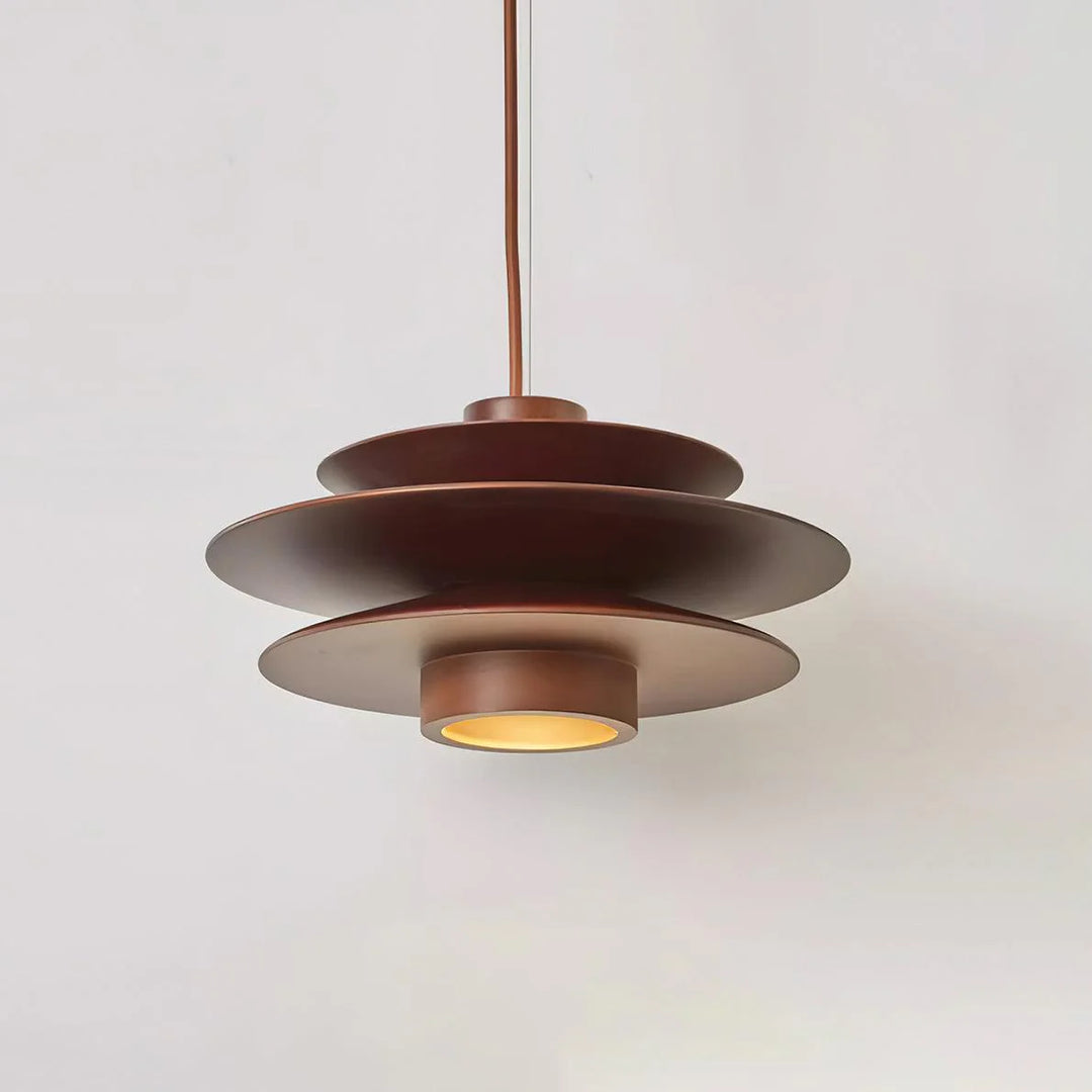 Cylindrical Pendant Light with a sleek layered metal design in a warm brown finish, suspended from a single cord, showcasing a contemporary style and soft downlight glow against a neutral background.