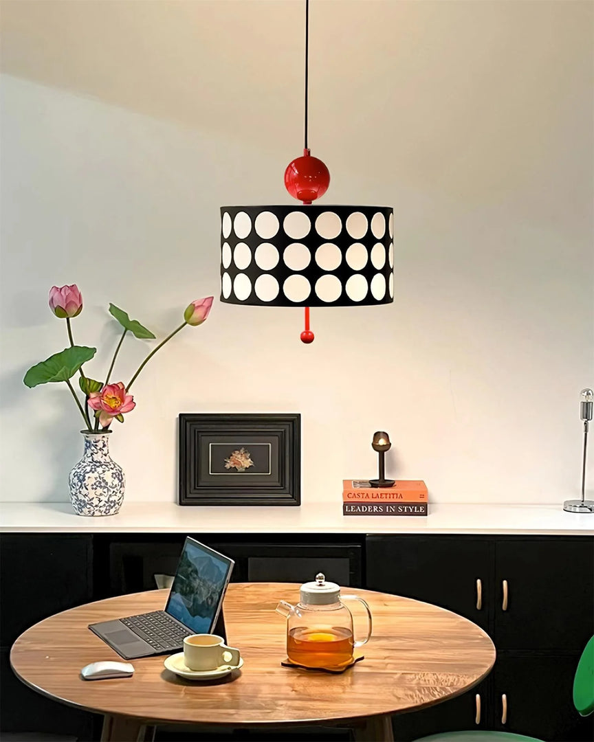 Stylish office setup showcasing a Metal Lattice Pendant Lamp with black and white patterned shade and red accents, hanging over a wooden table with a laptop, tea set, and decorative items, providing a modern and sophisticated atmosphere.