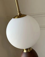 Load image into Gallery viewer, Close-up view of the Layali floor lamp’s frosted globe shade with brass detailing, highlighting its smooth matte finish and elegant metallic accents.
