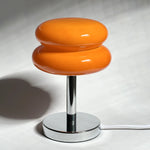 Load image into Gallery viewer, A vibrant orange Glossy Macaron Table Lamp with a sleek chrome base, featuring a glossy, smooth finish that adds a pop of color to modern interiors.
