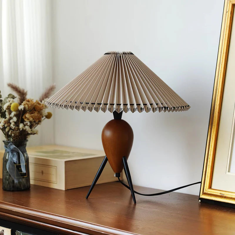 The Makie Table Lamp elegantly displayed on a wooden console, styled with a dried floral arrangement in a glass jar, a stack of books, and a golden picture frame in a cozy, modern space.