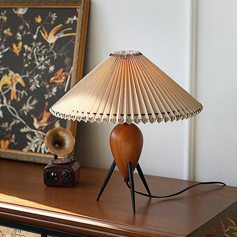 The Makie Table Lamp placed on a wooden console table with a decorative floral painting and a vintage speaker, enhancing the aesthetic with its warm ambient light.