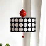 Load image into Gallery viewer, Modern metal lattice pendant lamp with a circular black shade featuring large white circles and a bright red spherical detail, hanging elegantly in a contemporary styled room.
