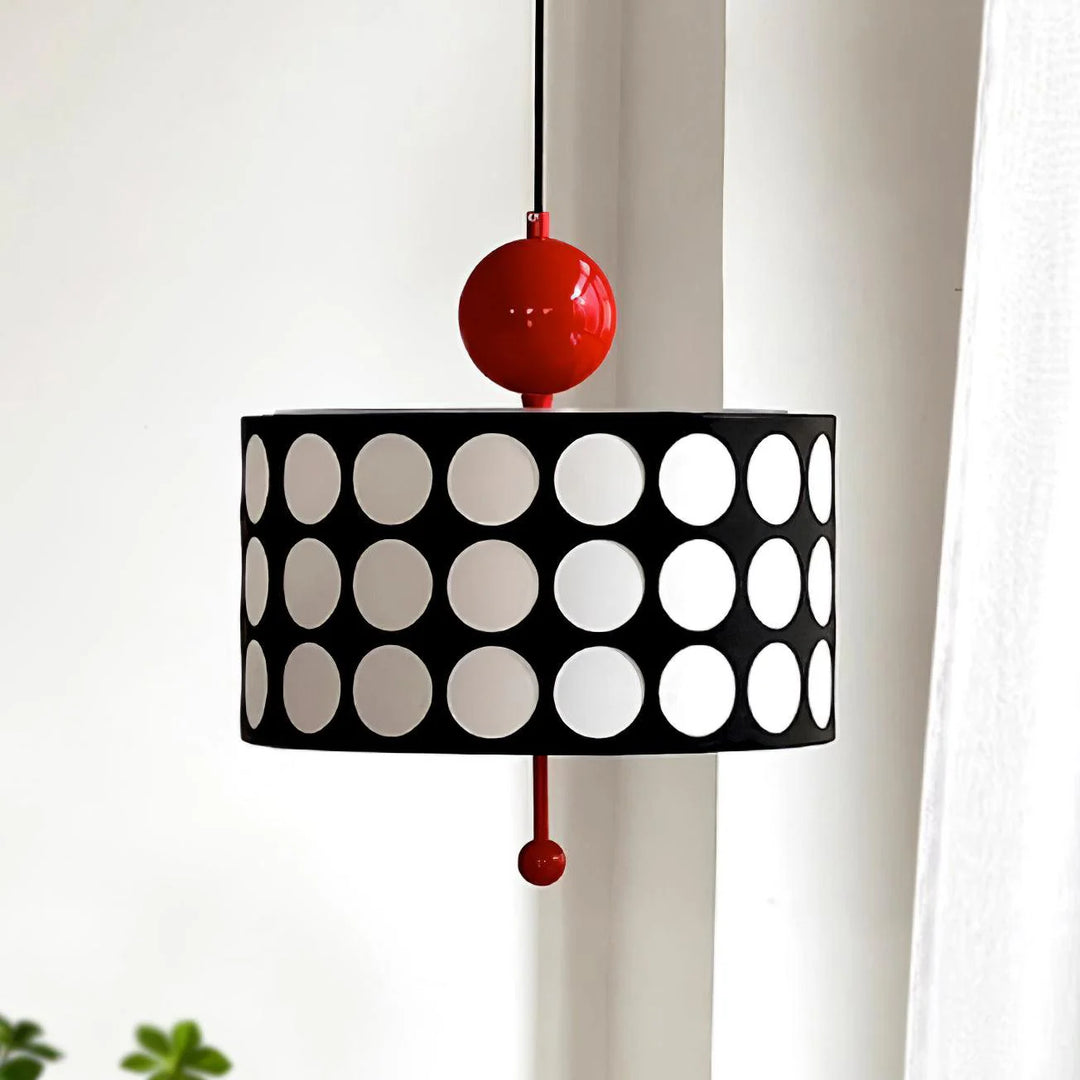 Modern metal lattice pendant lamp with a circular black shade featuring large white circles and a bright red spherical detail, hanging elegantly in a contemporary styled room.