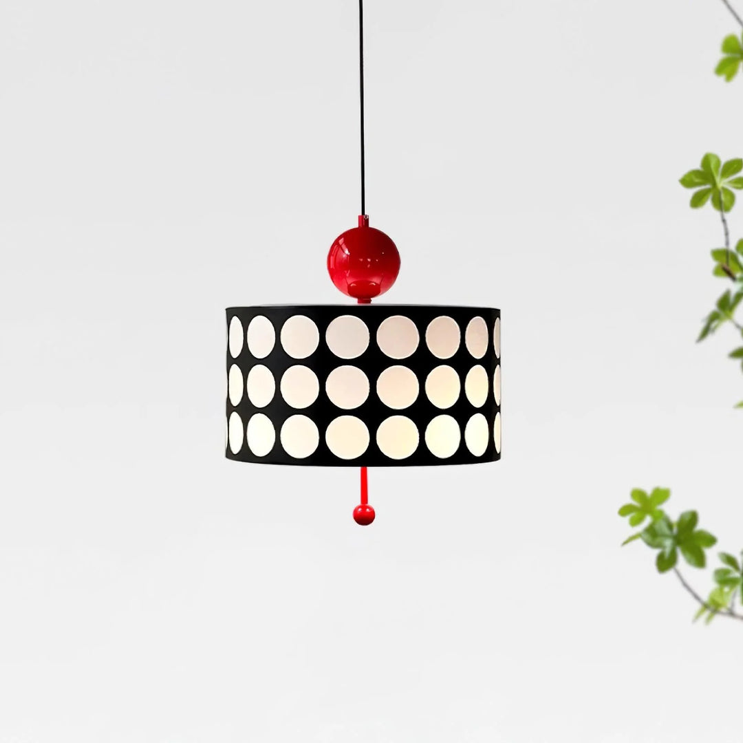 Simplistic yet striking Metal Lattice Pendant Lamp with black and white circular patterns and a bold red fixture, displayed against a crisp white background with a hint of green foliage, offering a clean and modern aesthetic.