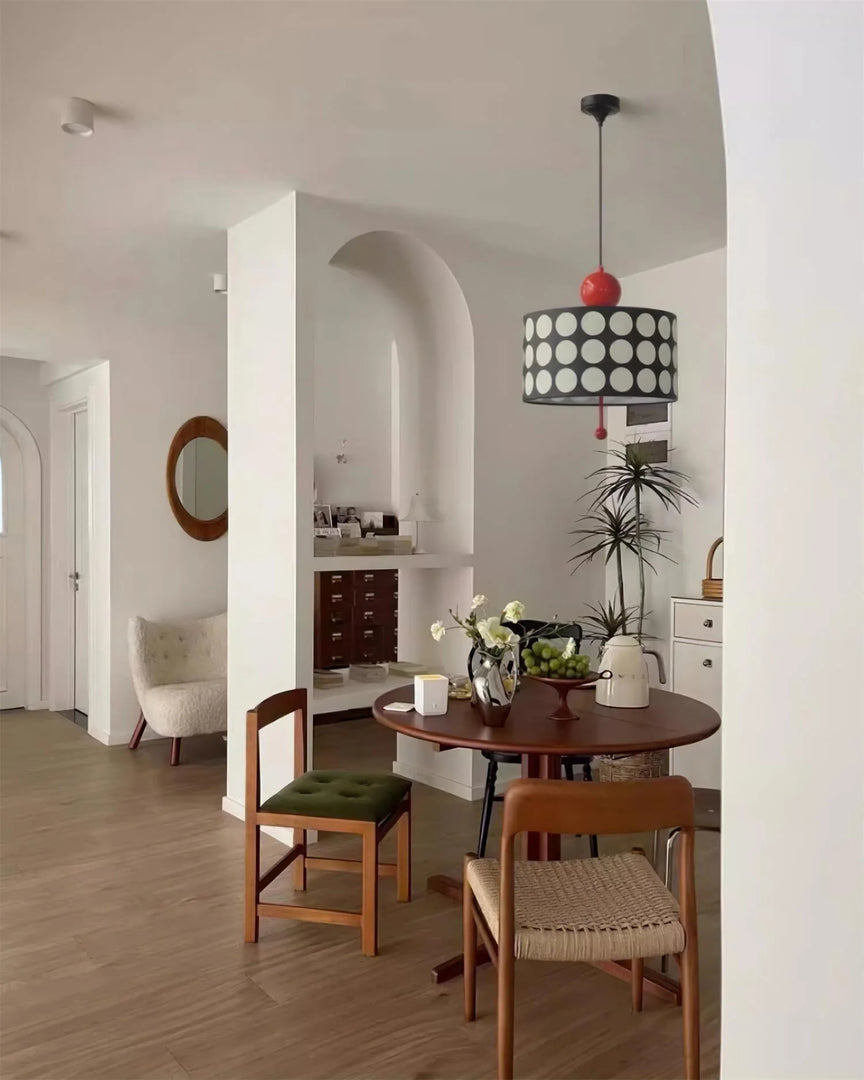 Elegant dining area featuring a Metal Lattice Pendant Lamp with a striking black and white circle pattern and red accents, perfectly complementing the warm wooden furniture and stylish interior decor.