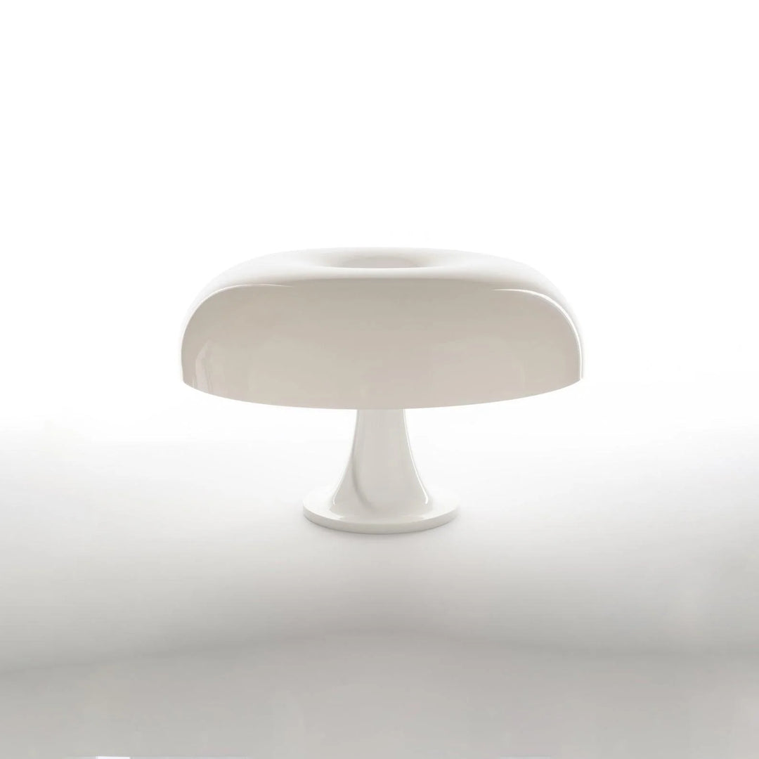 A sleek Mushroom Playful Table Lamp in pure white stands out with its smooth, simple silhouette against a stark white background, embodying minimalist elegance and modern design in a serene and uncluttered setting.