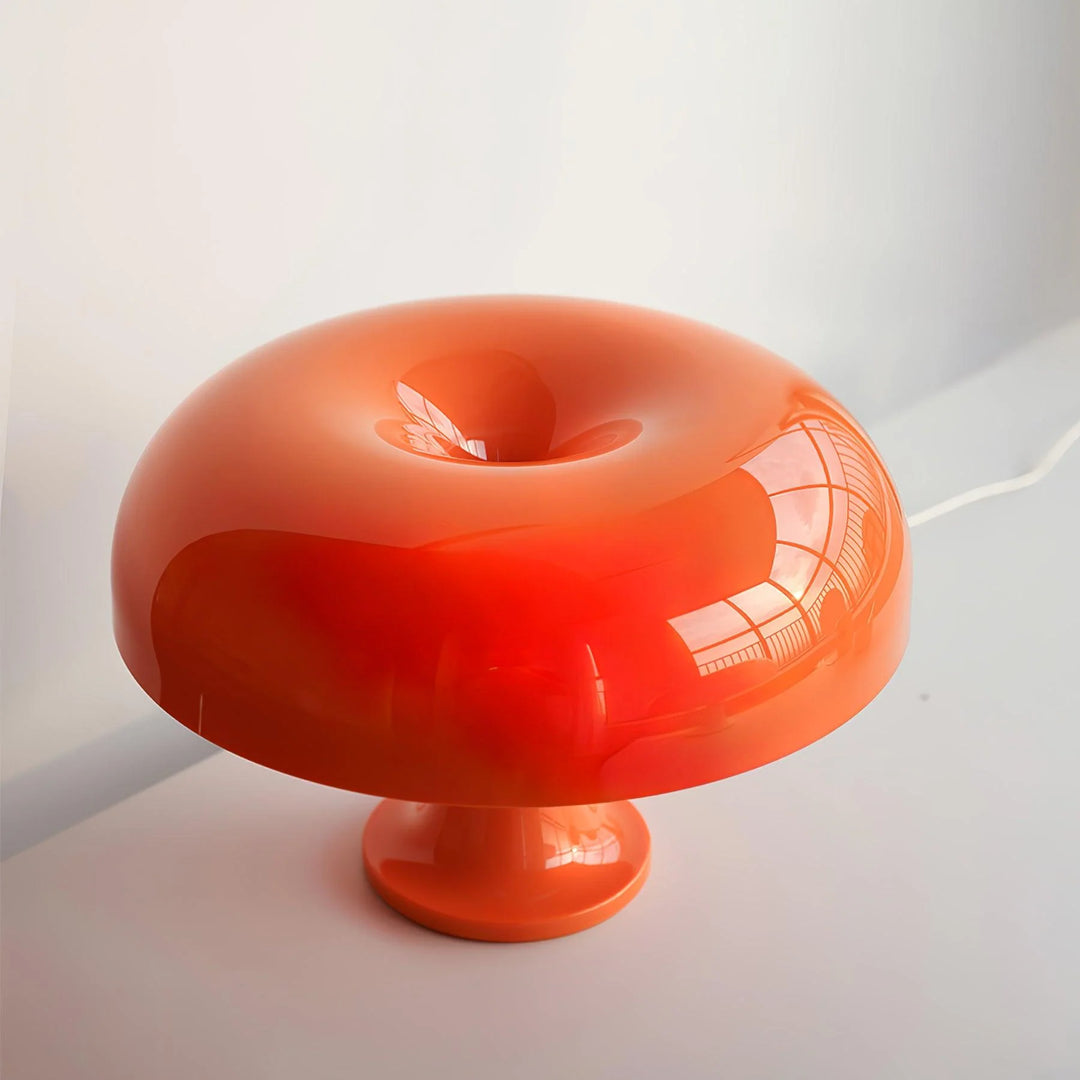 The Mushroom Playful Table Lamp in radiant orange offers a soft glow that highlights its smooth, sculptural form, creating a dramatic play of light and shadow in a minimalist setting, perfect for adding a bold statement to any modern decor.