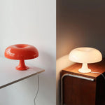 Load image into Gallery viewer, A side-by-side display of Mushroom Playful Table Lamps in contrasting colors—vibrant orange and soft cream—showcasing their sleek, iconic design in different lighting environments, highlighting their versatility and charm in modern home decor.
