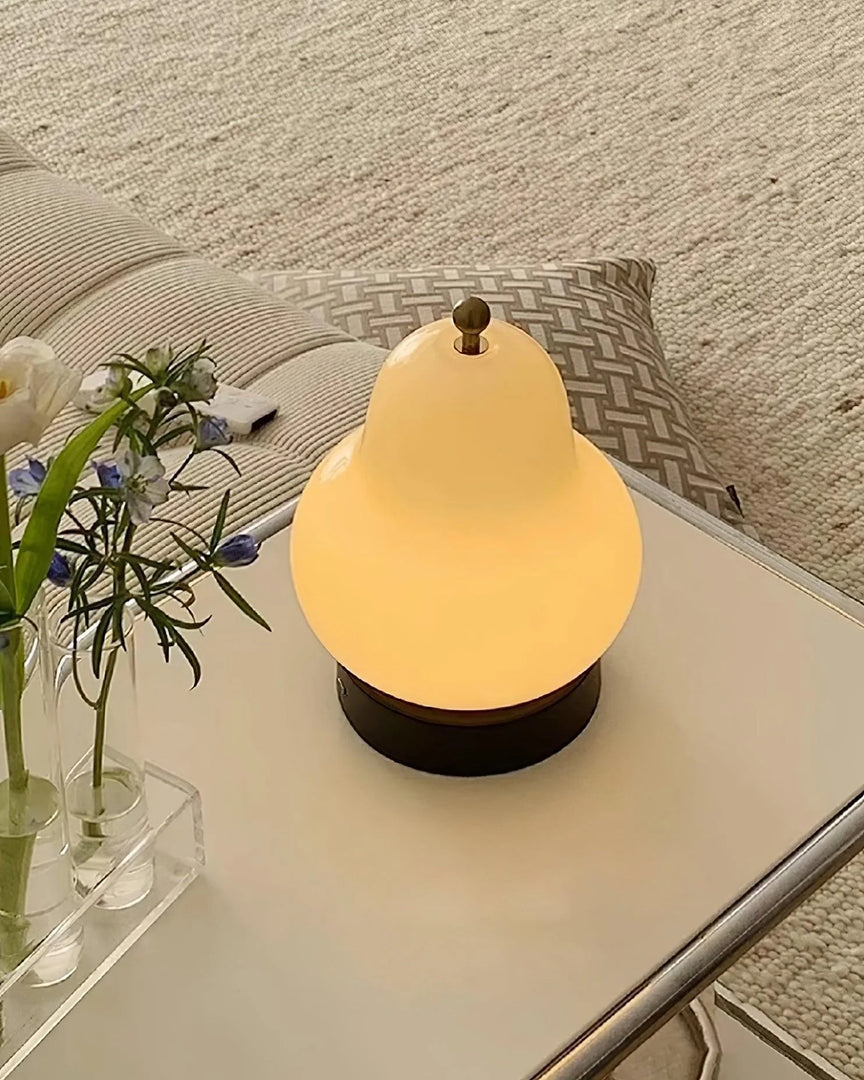 A pear-shaped lamp with a warm glow placed on a white coffee table, accompanied by a vase of fresh flowers and cozy cushions, creating an inviting and serene living room ambiance.