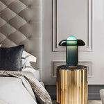 Load image into Gallery viewer, Persian green table lamp placed on a round, gold-toned side table in a luxurious bedroom with a tufted headboard, soft bedding, and elegant wall paneling.
