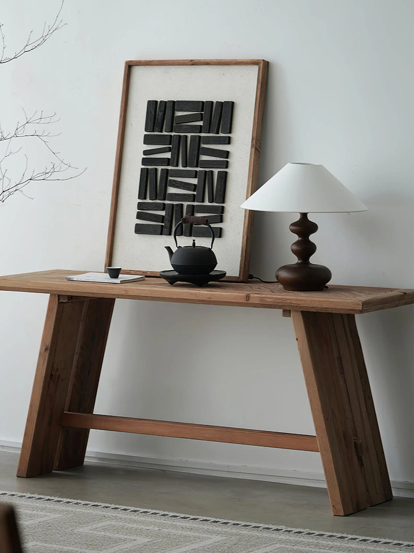 A rustic art studio setup featuring a Gourd Lamp with a dark wooden base and a simple white shade, perfectly complementing the aesthetic of the space. The lamp is set on a sturdy wooden table beside a traditional teapot and cup, with a striking black and white abstract art piece leaning against the wall, creating a harmonious blend of classic and contemporary styles.