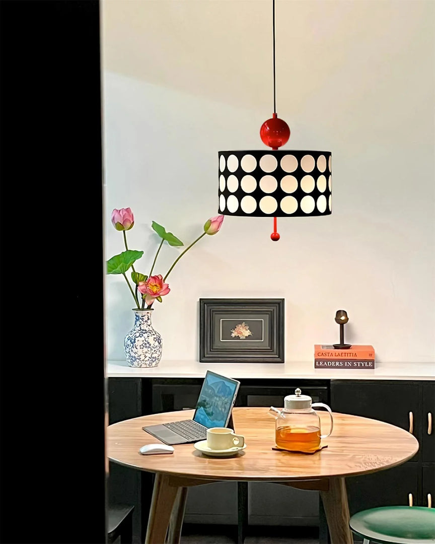 Chic modern office featuring a Metal Lattice Pendant Lamp with a black and white geometric shade and red accents, elegantly illuminating a wooden desk with a laptop, floral arrangement, and decorative items.