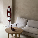 Load image into Gallery viewer, A Surfboard Floor Lamp featuring a sleek wooden design with three glowing panels, positioned next to a neutral-toned sofa and a round wooden coffee table with minimalist decor, set in a beige contemporary living space.
