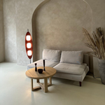 Load image into Gallery viewer, A Surfboard Floor Lamp with a mid-century modern design featuring a wooden frame and glowing panels, styled in a minimalist lounge with a neutral sofa, a round wooden coffee table, and dried decorative plants in a textured beige space.
