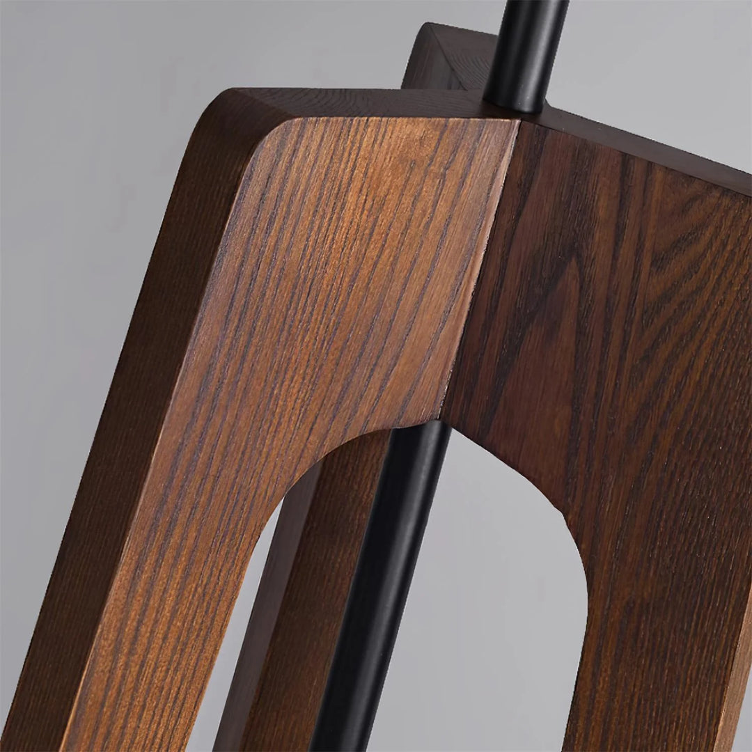 A close-up view of the wooden tripod base of a floor lamp, highlighting the natural grain texture and craftsmanship of the wood against a neutral background.