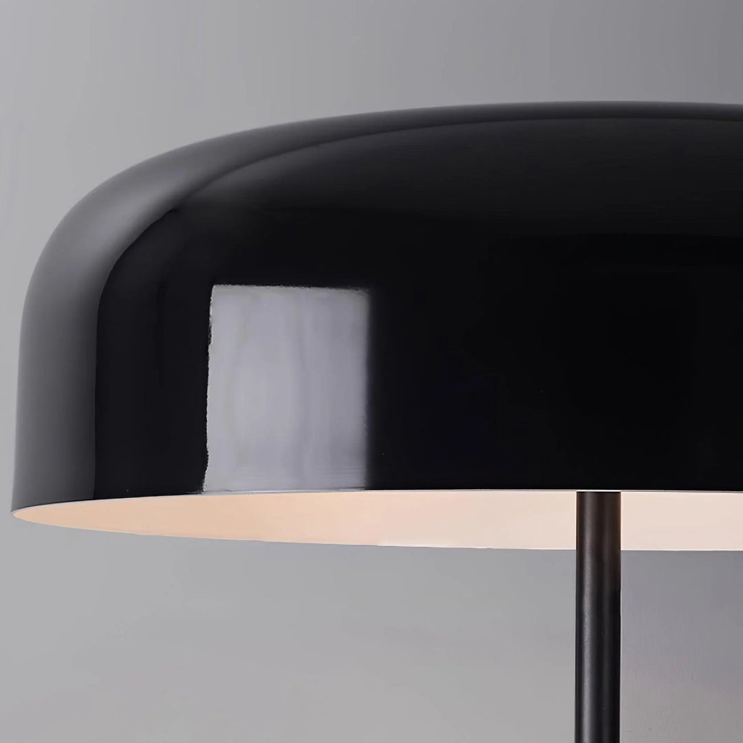 A close-up view of the black dome-shaped shade of a floor lamp, showcasing its glossy finish and sleek modern design against a neutral gray background.