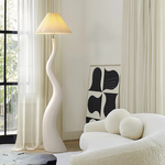 Load image into Gallery viewer, A wavy white floor lamp with a pleated shade, positioned in a bright, modern living space with sheer curtains, abstract artwork, and a plush curved sofa.
