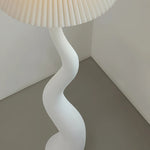 Load image into Gallery viewer, A modern wavy floor lamp with a unique spiral design and a pleated lampshade, placed in a minimalist corner setting.
